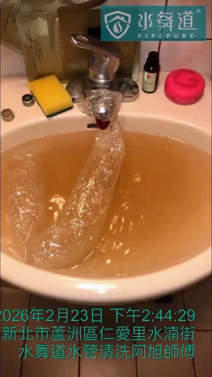 浴室洗手台正在進行水管清洗，從水龍頭流出的水使整個水槽呈現一片黃褐色的混濁狀態。