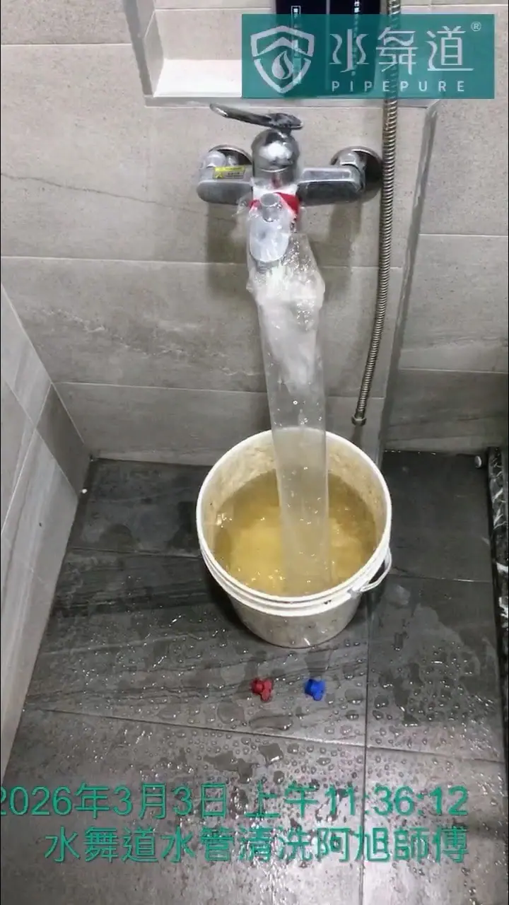 水管清洗作業中，從淋浴龍頭排出的水中可見明顯的片狀與顆粒狀沉積物。