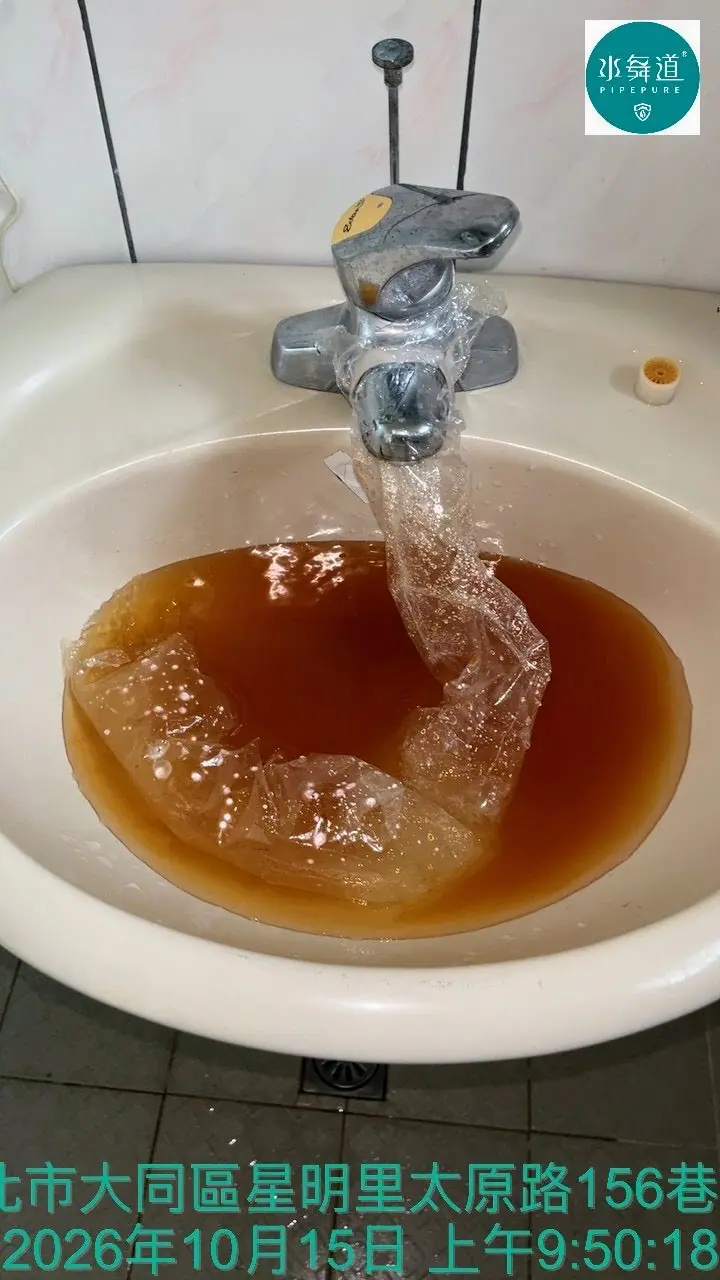 台北大同區52年公寓洗手台水龍頭清洗排水，透明集水袋與洗手盆內可見茶褐色水