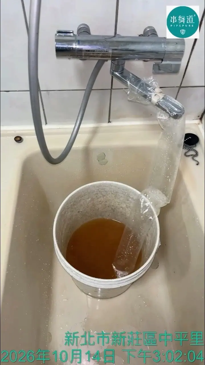新莊29年華廈水管清洗現場，浴缸水龍頭的透明導流套將褐色清洗水導入白色水桶